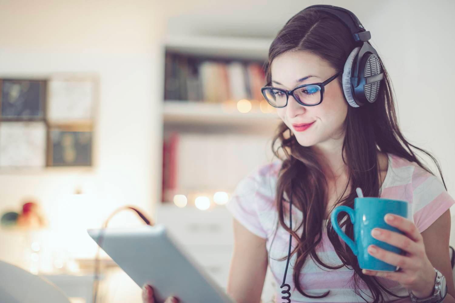 Woman smiling at screen while holding coffee cup