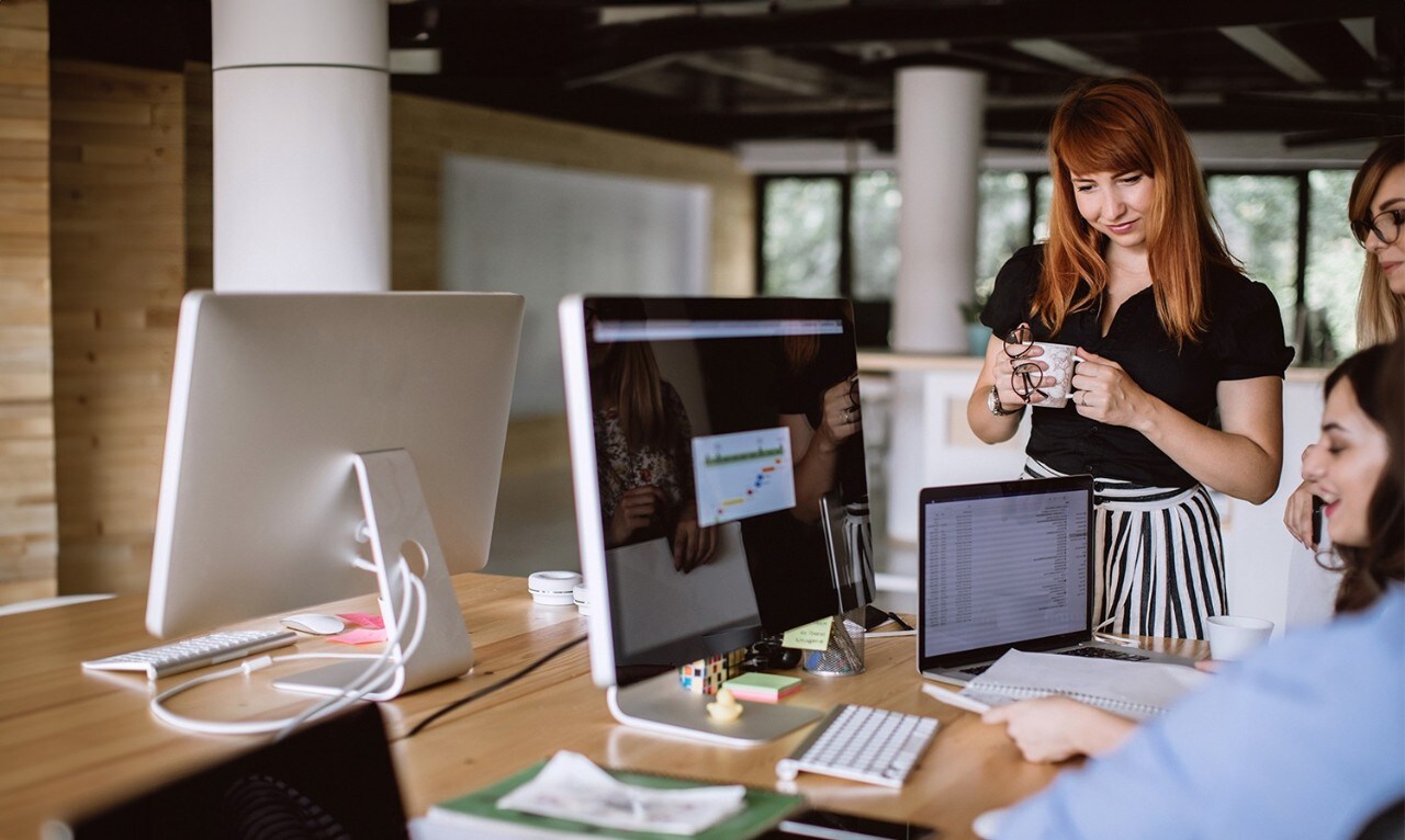 Woman holding coffee cup and smiling in team setting