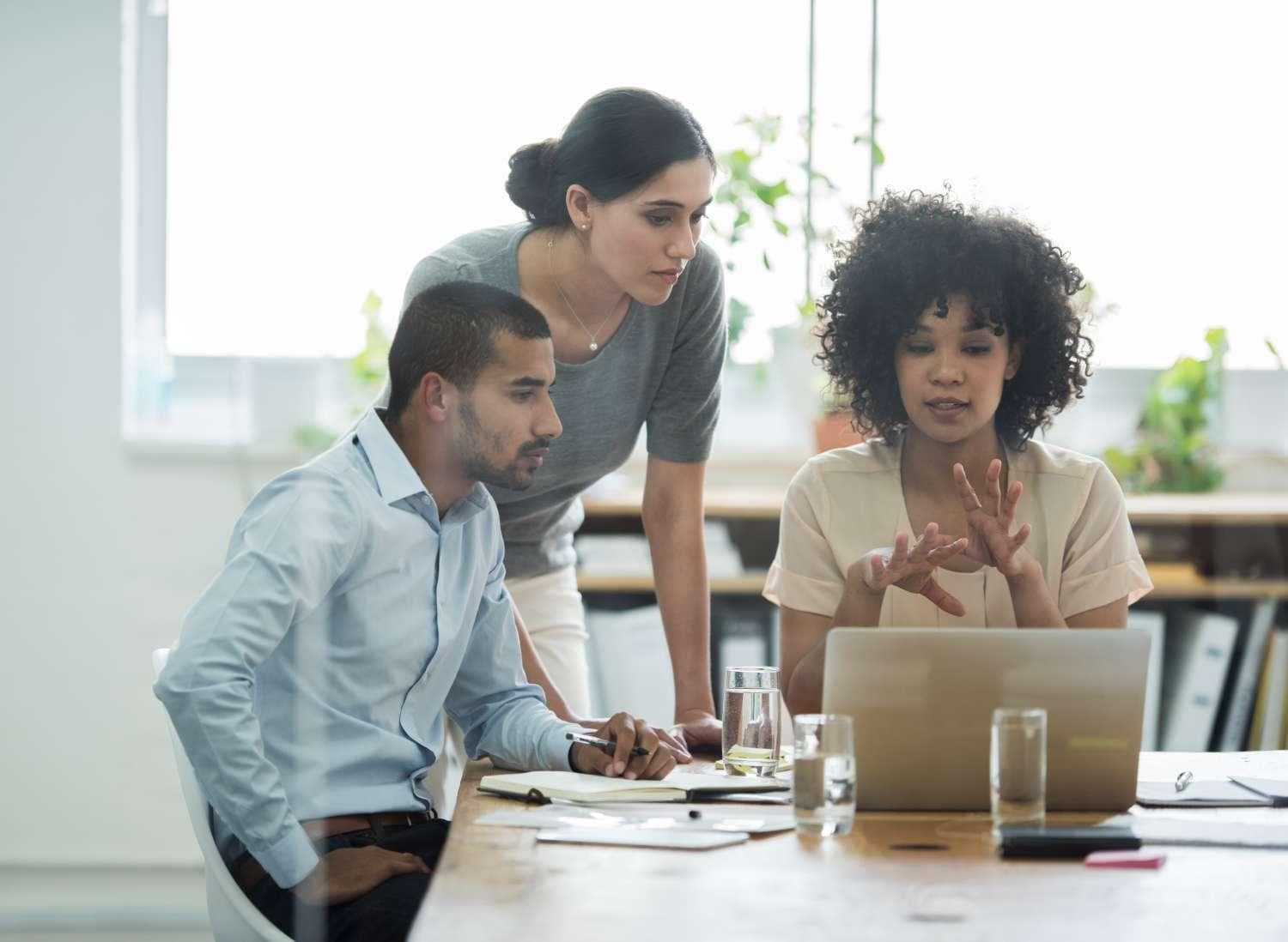 Two women and a man talking at laptop